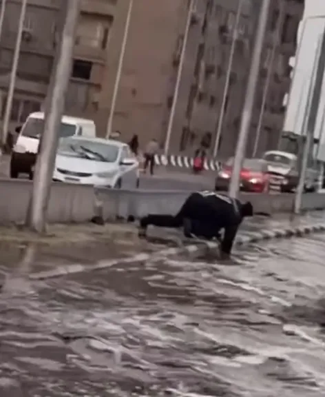 أمين شرطة تحت المطر.. شهامة وتفاني لإنقاذ الطريق من السيول